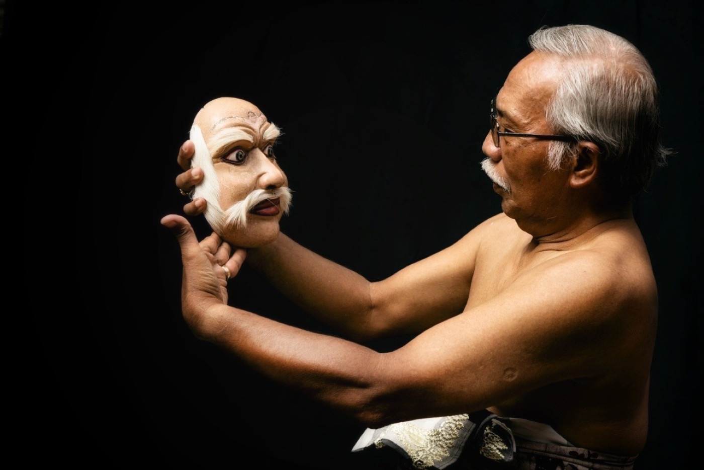 Master artist holding a traditional Balinese Topeng mask