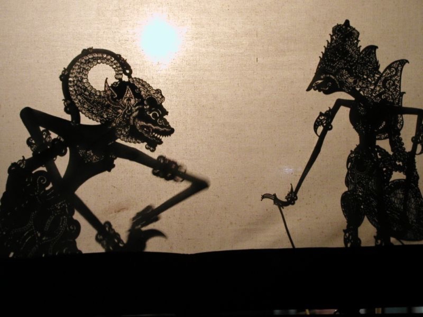 Balinese shadow puppets lit against a screen